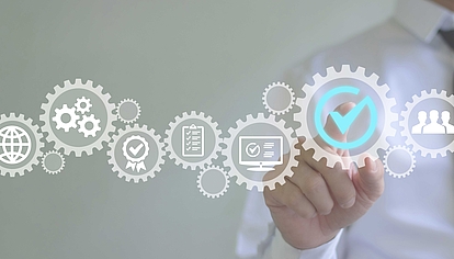 Quality Management and Process Optimization in the Digital Age Hand pointing at digital gear with check mark – symbolizes quality control, efficiency, and digital processes