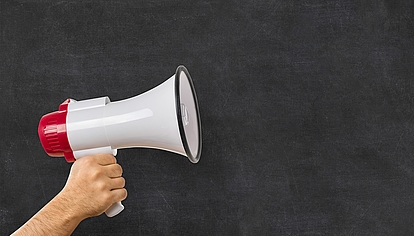 Newsroom and Company Updates Megaphone in front of a blackboard representing company news, press releases and event updates.